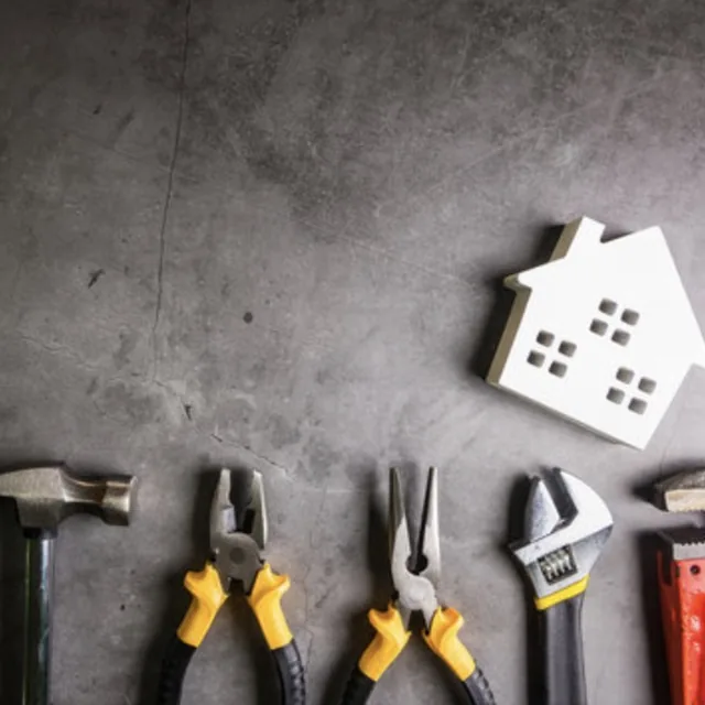 Hammer, pliers, wrenches, and a house-shaped cutout laid out for facility maintenance services in San Antonio